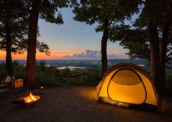 photo d'une tente, d'un hamac et d'un feu de bois dans un camping