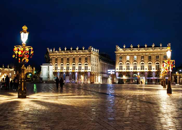 Place Stanislas de Nancy illuminée la nuit avec ses bâtiments et réverbères dorés