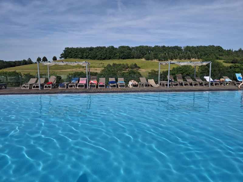 Piscine d’un camping 5 étoiles avec transats et vue sur la campagne verdoyante