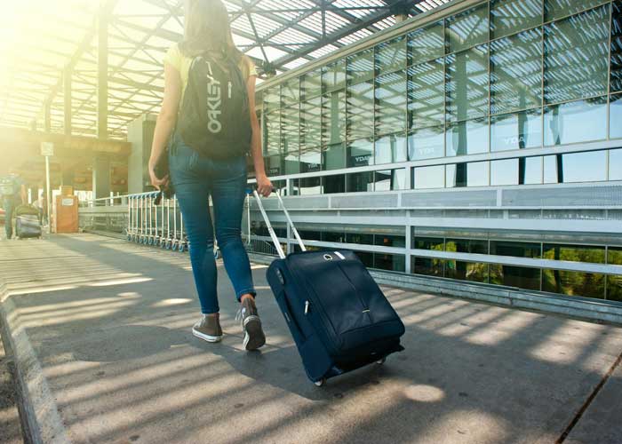 Voyageuse avec sac  dos et valise  roulettes marchant dans un aroport