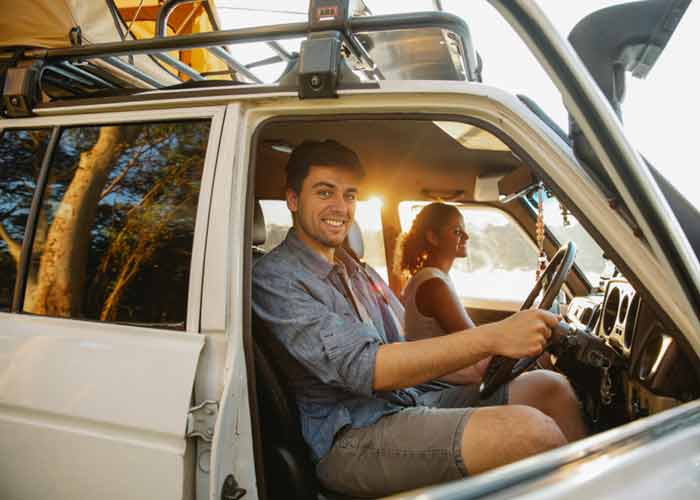 Jeune homme souriant au volant d�un 4x4 blanc pendant un road trip