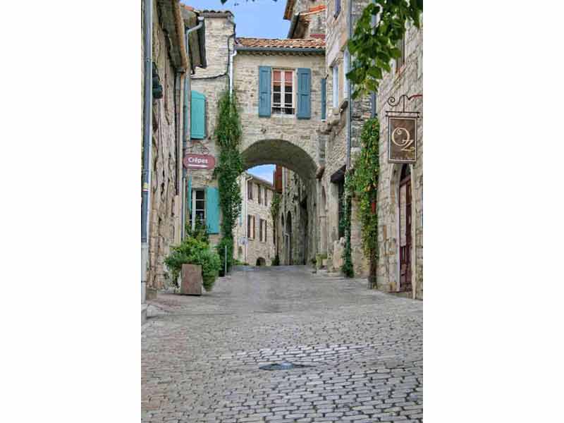 Ruelle pavée du village de Vézénobres dans les Cévennes, maisons en pierre et arche médiévale au cœur du village perché