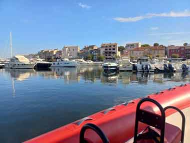 Vue sur des bateaux et des maisons qui bordent le port de Saint-Florent depuis une navette qui va jusqu'à la plage du Lotu (désert des Agriates, Corse, France)