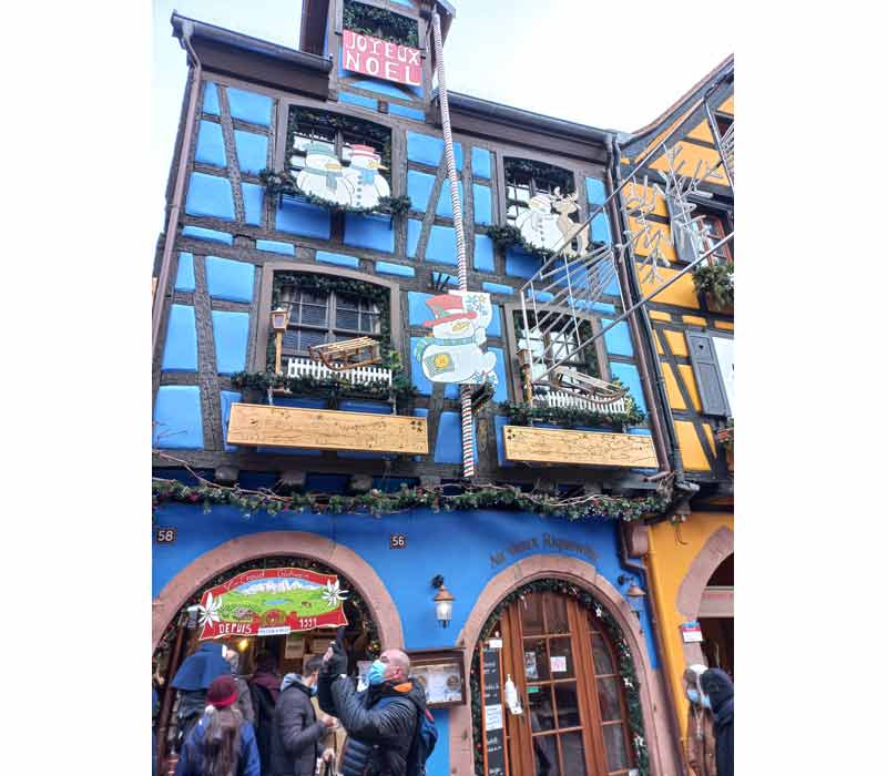 Façade colorée d’une maison à colombages à Riquewihr, décorée pour les fêtes de Noël en Alsace