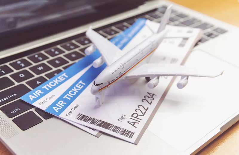 billets d’avion avec maquette d’avion posés sur un ordinateur portable pour réservation de voyage en ligne