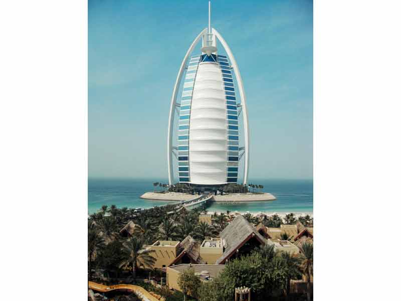 Vue emblématique du Burj Al Arab, hôtel de luxe en forme de voile, situé sur une île artificielle au large de Dubaï, 
							avec la mer en arrière-plan