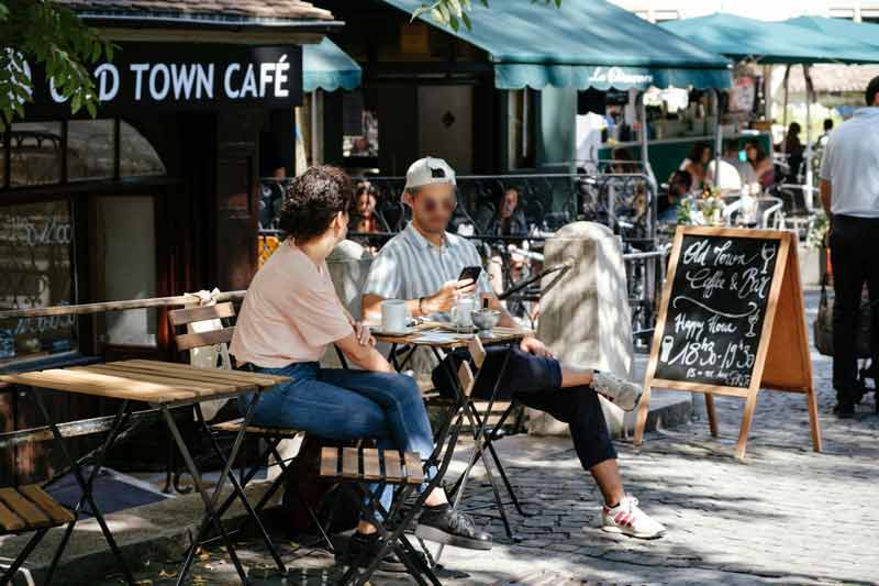 Terrasse de café dans la vieille ville de Genève avec personnes attablées en plein air