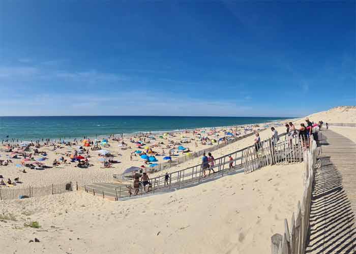 Plage de Hourtin animée sur la côte atlantique, vue panoramique entre dunes de sable, océan bleu et estivants profitant du soleil en Gironde