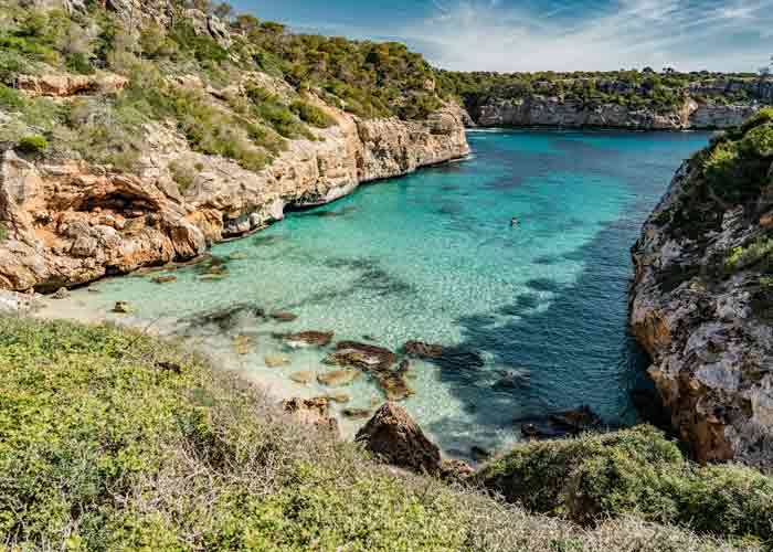 Vue paradisiaque de la plage de Caló des Moro avec ses eaux turquoise et ses falaises rocheuses