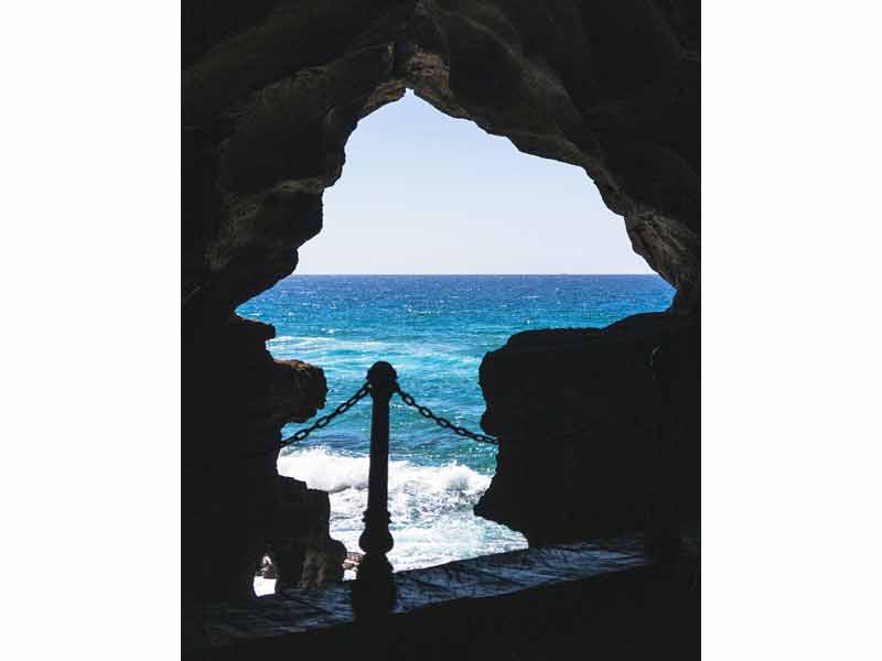 Vue emblématique des grottes d'Hercule à Tanger, avec l’ouverture rocheuse en forme de carte d’Afrique encadrant l’océan
							 Atlantique