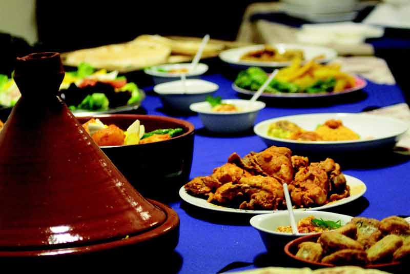 Table marocaine dressée à Tanger avec un tajine en terre cuite et un assortiment de plats traditionnels, dont des viandes 
							épicées, des salades et des accompagnements colorés